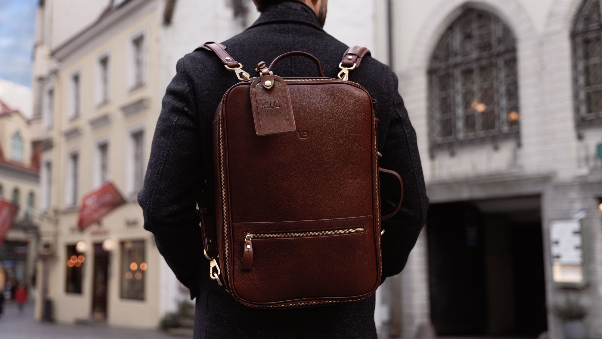 Von Baer 10x high-quality leather travel backpack in brown, worn by a handsome man, slider.