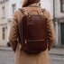 Von Baer 10X high-quality leather travel backpack in brown for laptop, carried by a woman in an old town setting.