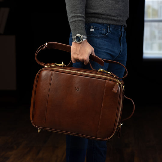 Von Baer 10x luxury leather laptop travel backpack in brown, held in the hands of a male model.