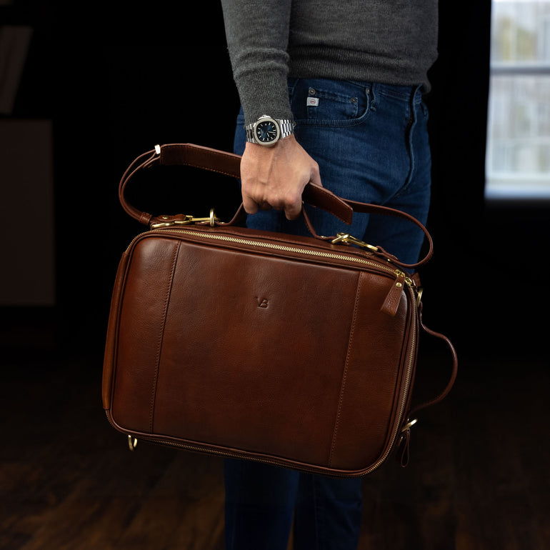 Von Baer 10x luxury leather laptop travel backpack in brown, held in the hands of a male model.