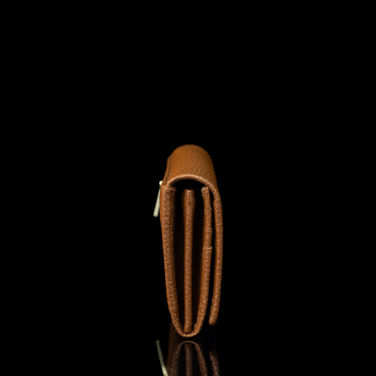 Von Baer Allure large cognac tan full-grain leather accordion wallet with RFID protection, shown in a back view highlighting the zipped outer pocket with a gold-tone zipper against a black background.