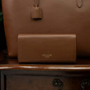 Von Baer Allure large tan full-grain leather accordion wallet displayed with a matching tan leather tote bag in the background.