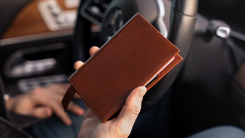Von Baer Atlas full-grain leather passport holder in brown held in hands with cards, luxury travel accessory.