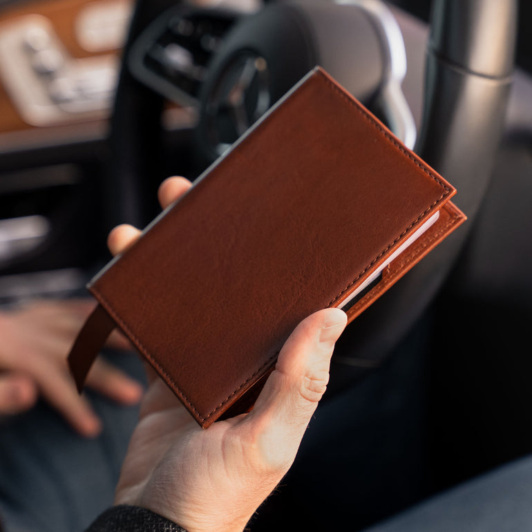 Von Baer Atlas full-grain leather passport holder in brown held in hands with cards, premium travel accessory for professionals.