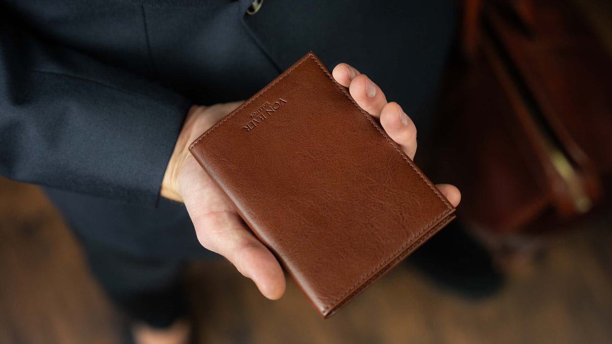 Von Baer Atlas full grain leather passport holder held by a gentleman in a navy blue suit
