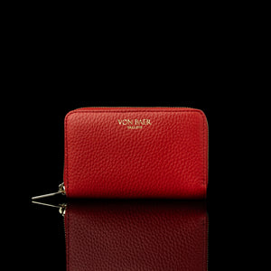 Von Baer Celeste small red full-grain leather zip-around wallet with gold-tone branding, displayed in a front view against a black background.