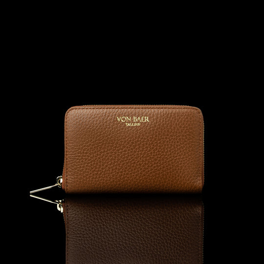 Von Baer Celeste small tan full-grain leather zip-around wallet with a gold-tone zipper, displayed in a front view against a black background.