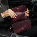 Von Baer Celeste small burgundy full-grain leather zip-around wallet demonstrated inside the Isabella small leather crossbody bag interior, held open inside a car setting with gold-tone hardware and gold-embossed Von Baer Tallinn branding.