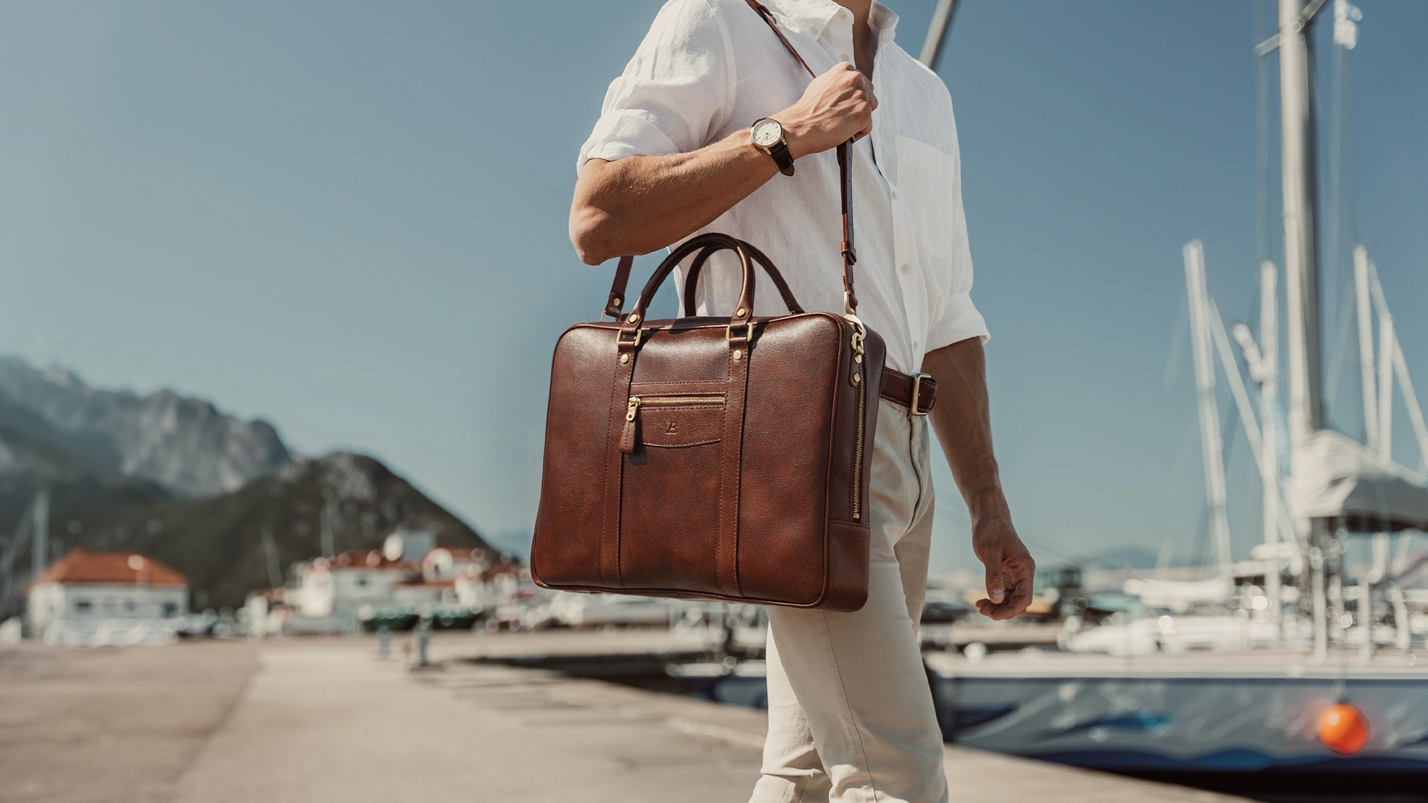 von baer city large leather laptop bag luxury design brown with shoulder strap in hands of stylish male model in harbour slider