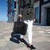 A beautiful woman holding a black Von Baer City luxury leather laptop bag in a city setting.