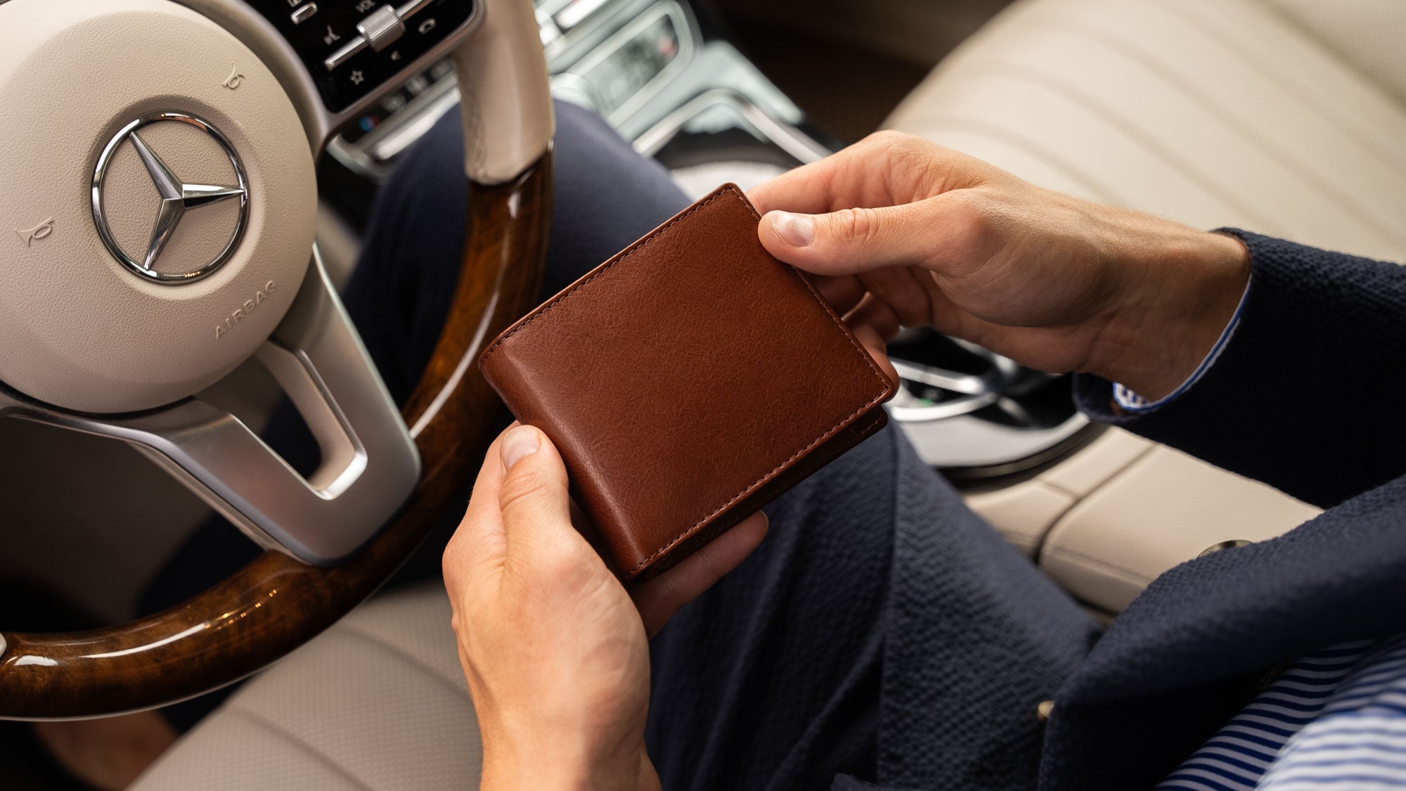 Von Baer Classic bifold luxurious brown leather wallet held by businessman in car slider view