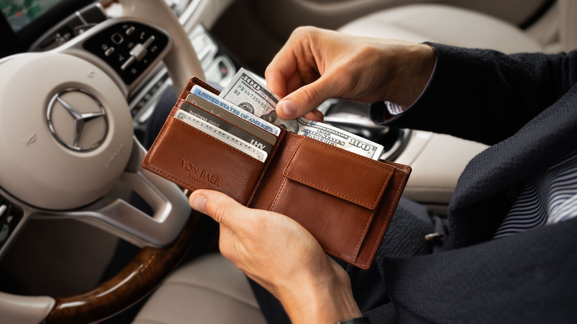Von Baer Classic bifold luxurious brown leather wallet filled with bank and credit cards, man taking out dollars in Porsche slider view