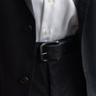 Von Baer classic luxury full-grain leather belt for men in black, with a buckle, worn with a black suit.