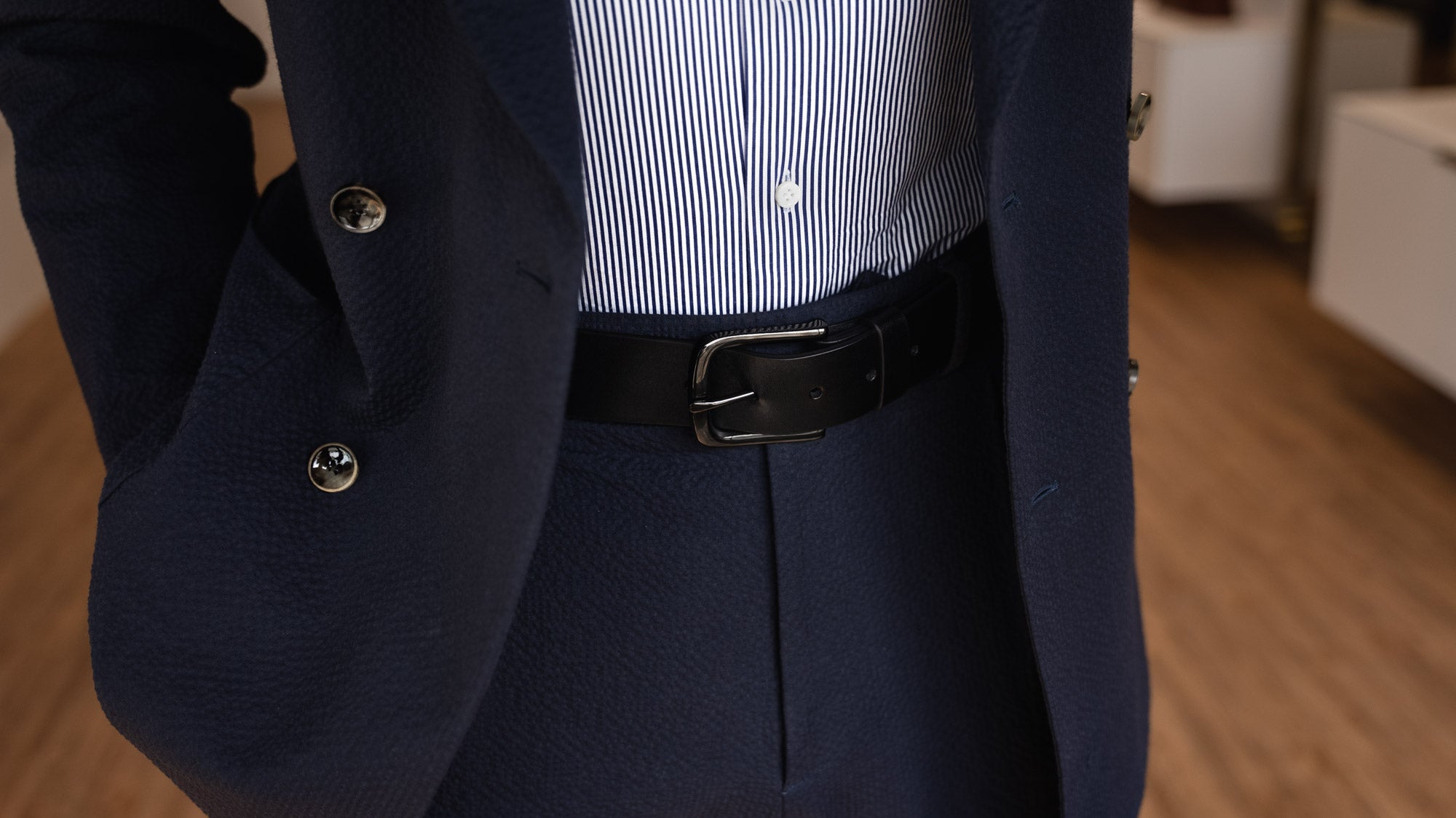 Von Baer classic luxury full-grain leather belt for men in black, with a buckle, worn with a navy blue suit.