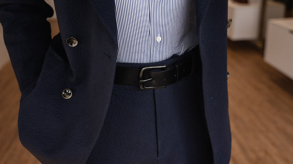 Von Baer classic luxury full-grain leather belt for men in black, with a buckle, worn with a navy blue suit.
