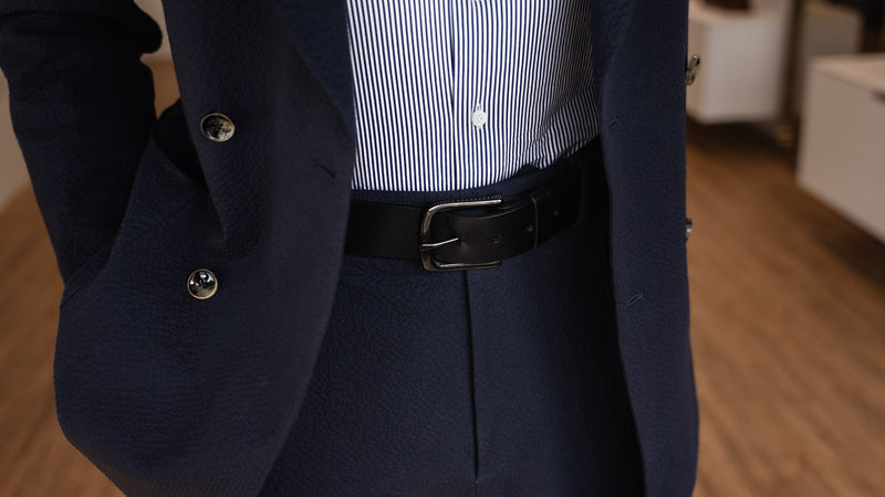 Von Baer classic luxury full-grain leather belt for men in black, with a buckle, worn with a navy blue suit.