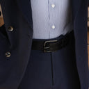Von Baer classic luxury full-grain leather belt for men in black, with a buckle, worn with a navy blue suit.
