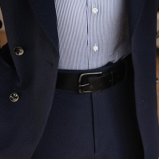 Von Baer classic luxury full-grain leather belt for men in black, with a buckle, worn with a navy blue suit.