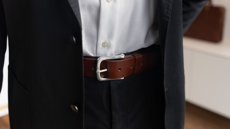 Von Baer classic luxury full-grain leather belt for men in brown, with a silver stainless steel buckle, worn with a black suit.