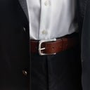 Von Baer classic luxury full-grain leather belt for men in brown, with a silver stainless steel buckle, worn with a black suit.