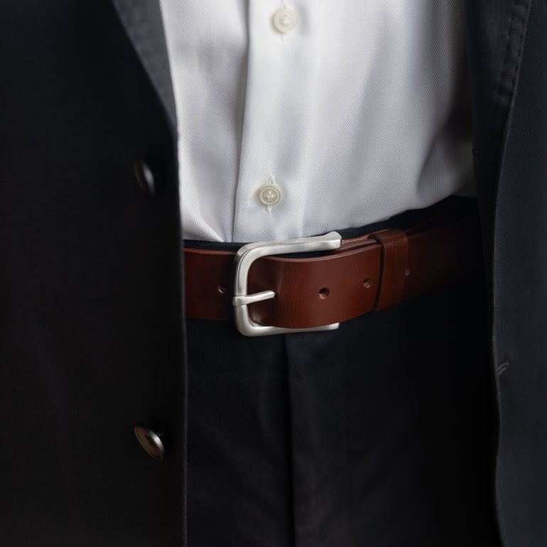 Von Baer classic luxury full-grain leather belt for men in brown, with a silver stainless steel buckle, worn with a black suit.