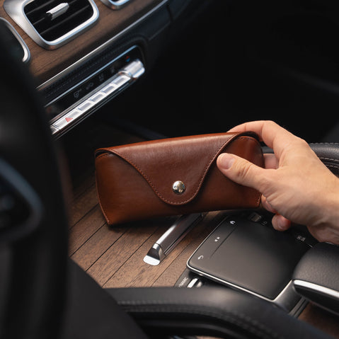 A brown Von Baer Deluxe luxury leather sunglasses and glasses case in a car.
