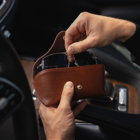 A brown Von Baer Deluxe luxury leather sunglasses and glasses case in a car, with glasses being taken out.