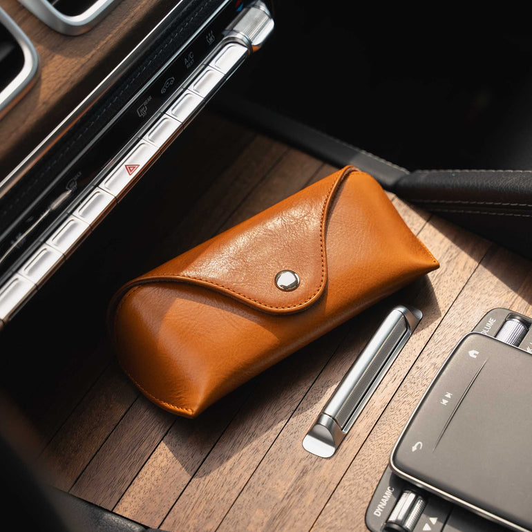 A front-side view of a tan Von Baer Deluxe luxury leather sunglasses and glasses case on a wooden panel in a car.