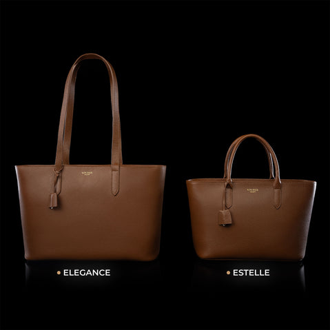 Von Baer Elegance and Estelle women's full-grain leather tote bags in cognac and tan, displayed side by side on a black background to compare sizes, featuring matching top handles, hanging leather tags, and gold-tone logo plaques, with the larger Elegance bag on the left and the smaller Estelle bag on the right