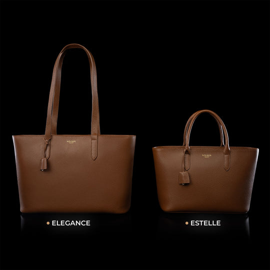 Von Baer Elegance and Estelle women's full-grain leather tote bags in cognac and tan, displayed side by side on a black background to compare sizes, featuring matching top handles, hanging leather tags, and gold-tone logo plaques, with the larger Elegance bag on the left and the smaller Estelle bag on the right