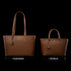 Von Baer Elegance and Estelle women's full-grain leather tote bags in cognac and tan, displayed side by side on a black background to compare sizes, featuring matching top handles, hanging leather tags, and gold-tone logo plaques, with the larger Elegance bag on the left and the smaller Estelle bag on the right