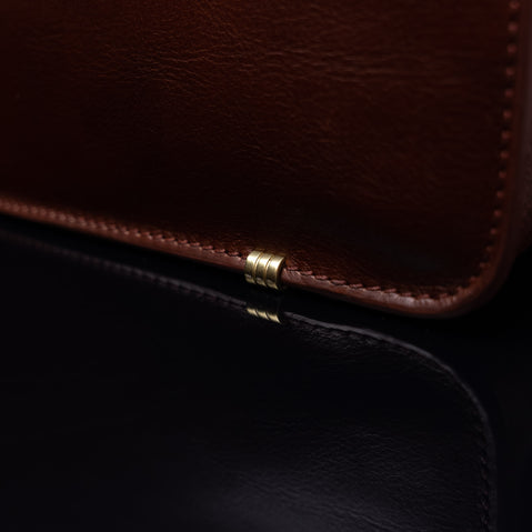 Von Baer Elegant high-quality slim full-grain leather women’s laptop bag in brown, close-up showing protective metal feet.