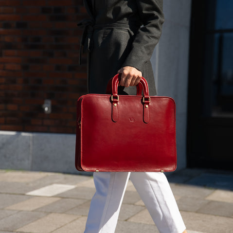 A woman dressed in a casual suit holding a red Von Baer elegant luxury leather laptop bag.