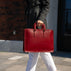 A woman dressed in a casual suit holding a red Von Baer elegant luxury leather laptop bag.