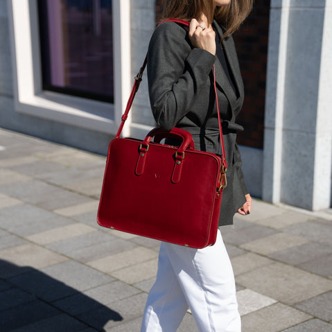 A good-looking woman in a business suit holding a black Von Baer elegant luxury leather laptop bag with a shoulder strap.
