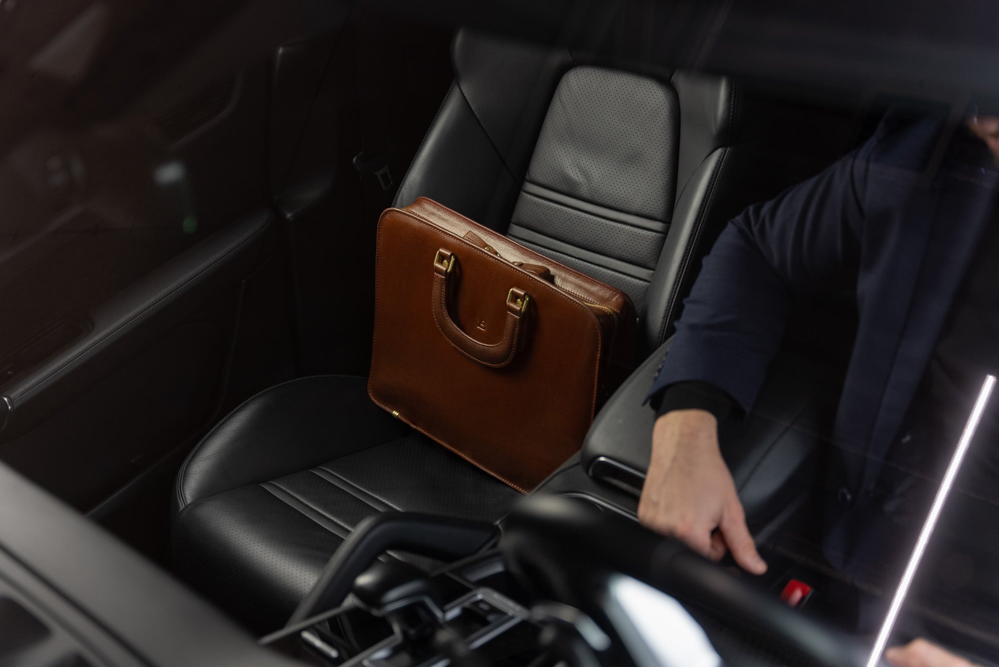 A Von Baer elegant luxury slim full-grain leather laptop bag is shown inside a Porsche.