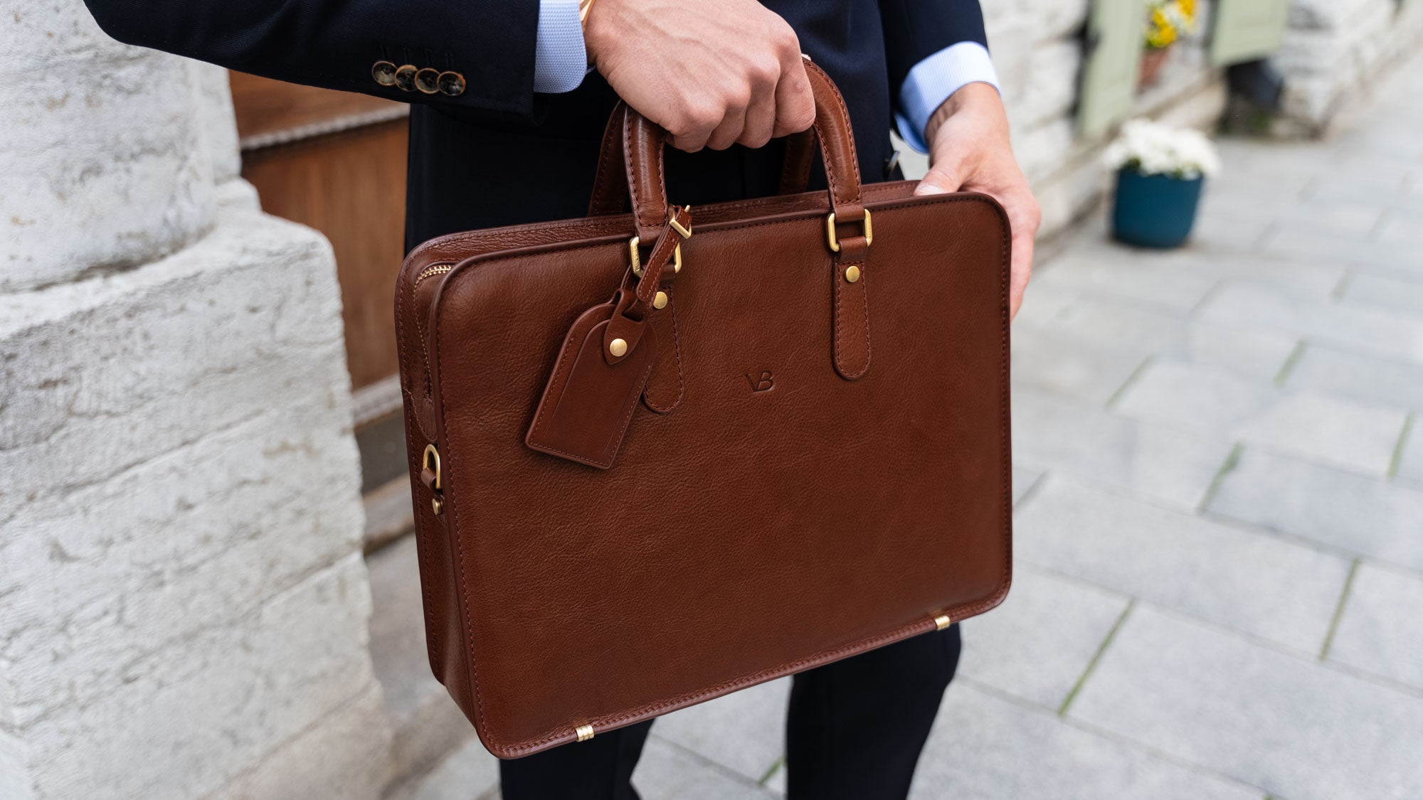 A businessman holding an elegant Von Baer brown slim leather laptop bag with a luggage tag, showcasing a traditional style.