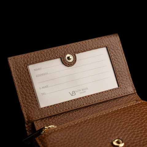 Von Baer Elise women's cognac pebbled leather trifold wallet displayed open to show a gold-tone snap button, an ID window with an insert card, and gold logo detailing.