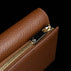 Von Baer Elise women's cognac pebbled leather trifold wallet shown in a close-up detail shot on a solid black background, featuring gold-tone zipper hardware and a monogram zipper pull.