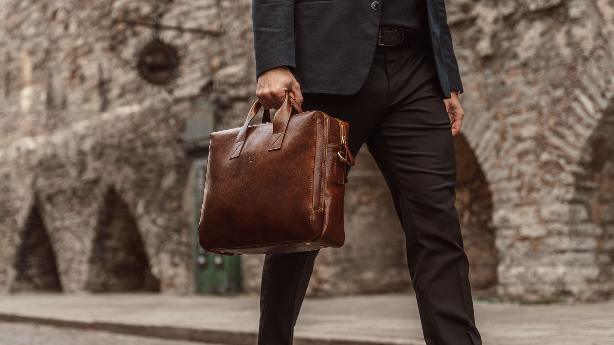 A male model in a suit is shown with a solid brown Von Baer Essential Italian leather briefcase for a laptop.