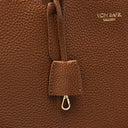 Close-up of a brown pebbled leather bag with a hanging leather tab and metal clasp, featuring the gold-toned embossed brand name VON BAER on the upper right.