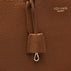 Close-up of a brown pebbled leather bag with a hanging leather tab and metal clasp, featuring the gold-toned embossed brand name VON BAER on the upper right.