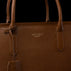 Close-up of a brown pebbled leather tote bag with gold-toned 'VON BAER' branding on the front, set against a solid black background.