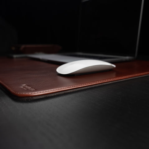 Von Baer executive durable leather desk pad, brown, on a dark wood table, side view showcasing its thickness.