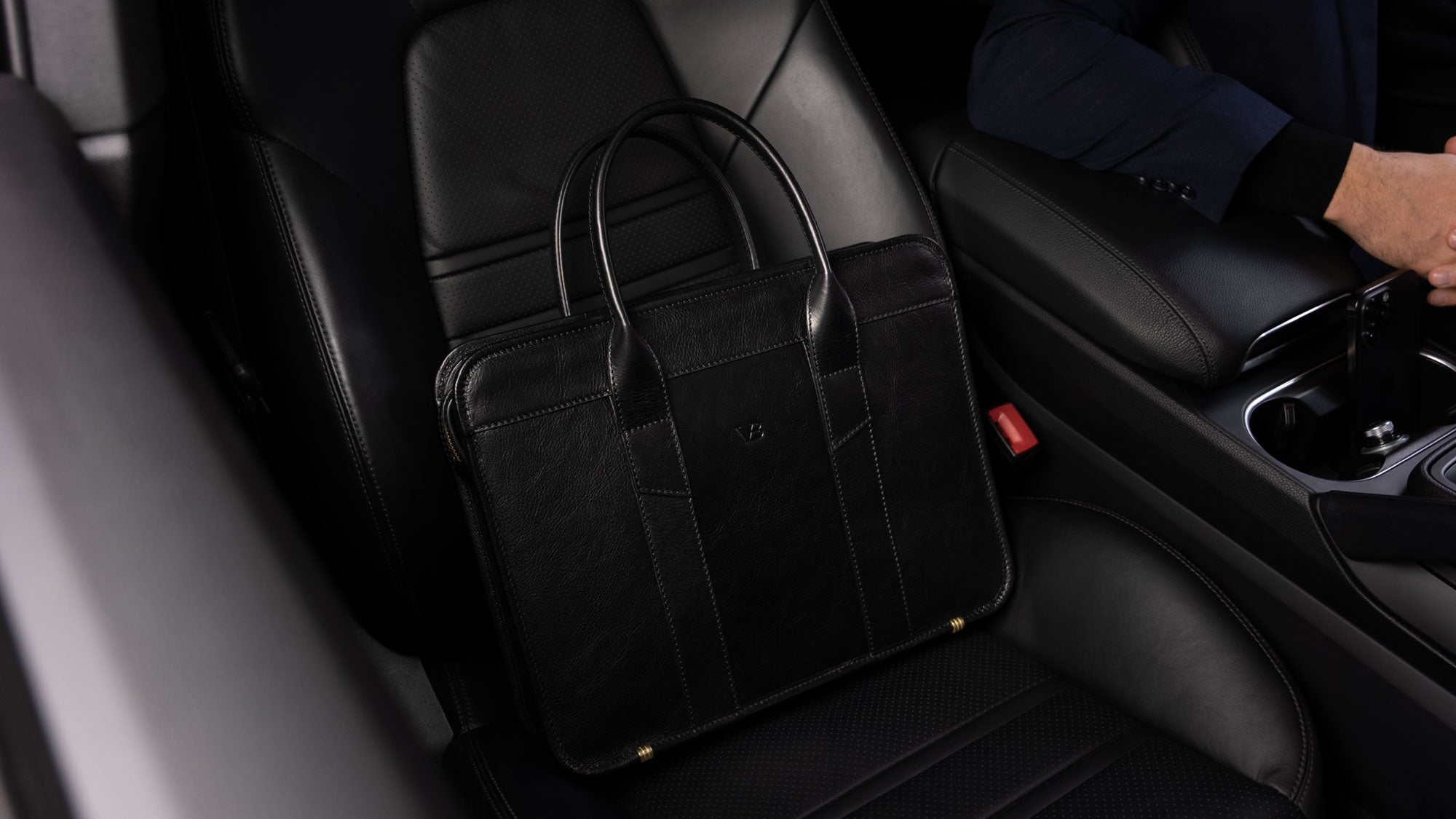 Von Baer exquisite luxury slim full-grain leather laptop bag on the seat of a Porsche car, slider view.