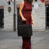 A beautiful woman in red holding a black Von Baer exquisite luxury leather laptop bag.