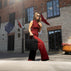 A beautiful woman in red holding a black Von Baer exquisite luxury leather laptop bag, with a building and flags in the background.