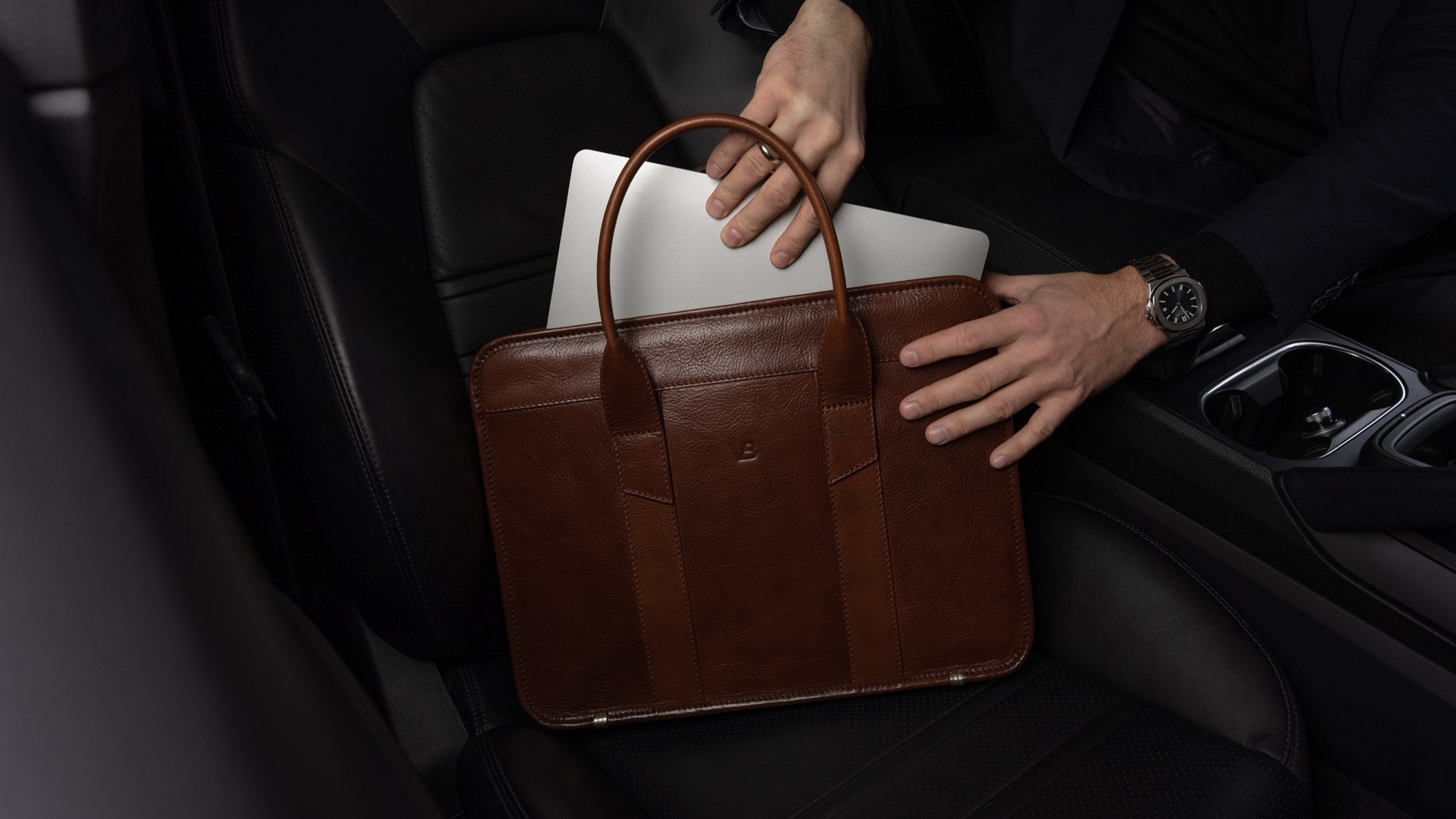 Von Baer Exquisite luxury slim full-grain leather laptop bag, businessman taking out a MacBook in a Porsche car, slider view.