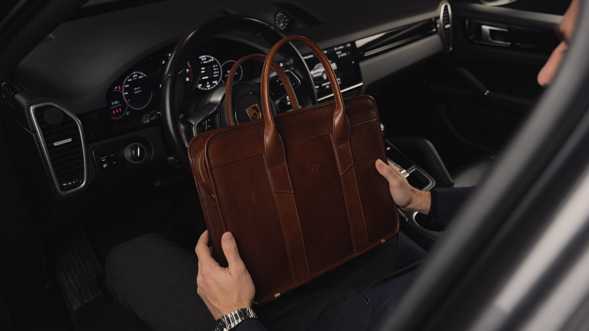 Von Baer Exquisite luxury slim full-grain leather laptop bag in the Porsche, held by a rich man, slider view.