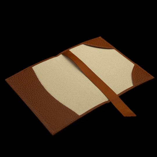 Von Baer full grain leather passport cover holder in cognac tan color, inside view laying on a table against black background